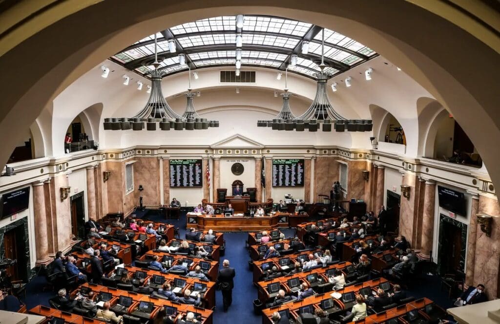 A view of the Kentucky State Capitol’s House chamber, showcasing rows of wooden desks and chairs under a vaulted ceiling with classical detailing. The decor, featuring warm tones and dignified design, reflects the civic stage where how Democrats win in Kentucky can begin to take shape.